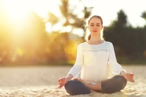 Person sitzt im Schneidersitz und probiert eine Meditationstechnik aus